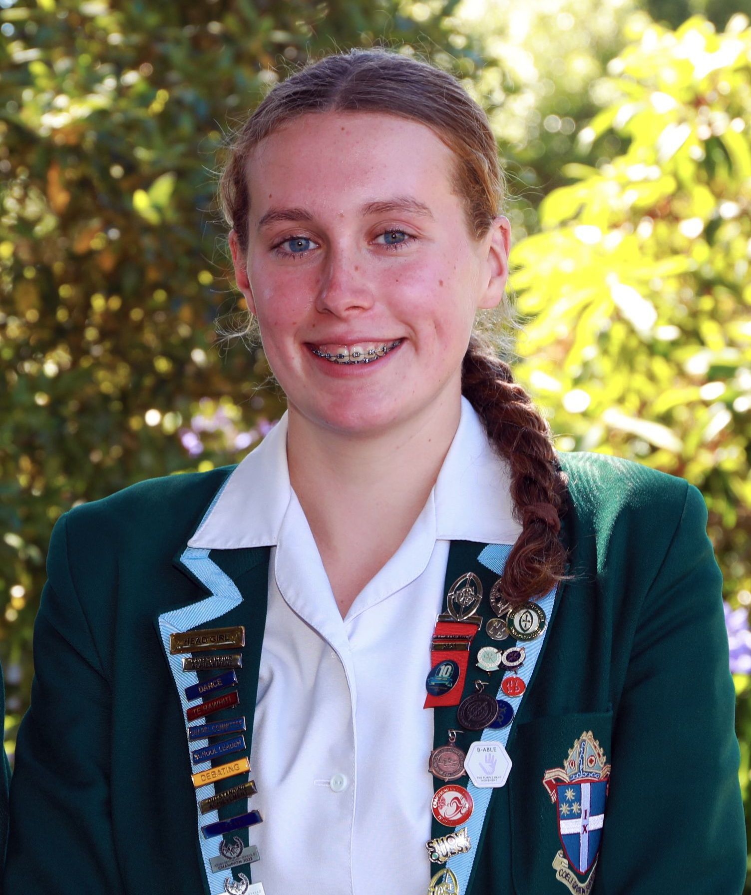 A girl wearing a green jacket and a white shirt is smiling