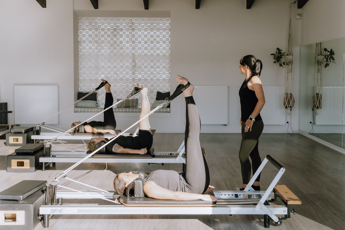 A woman is teaching a group of people how to do pilates on a pilates machine.