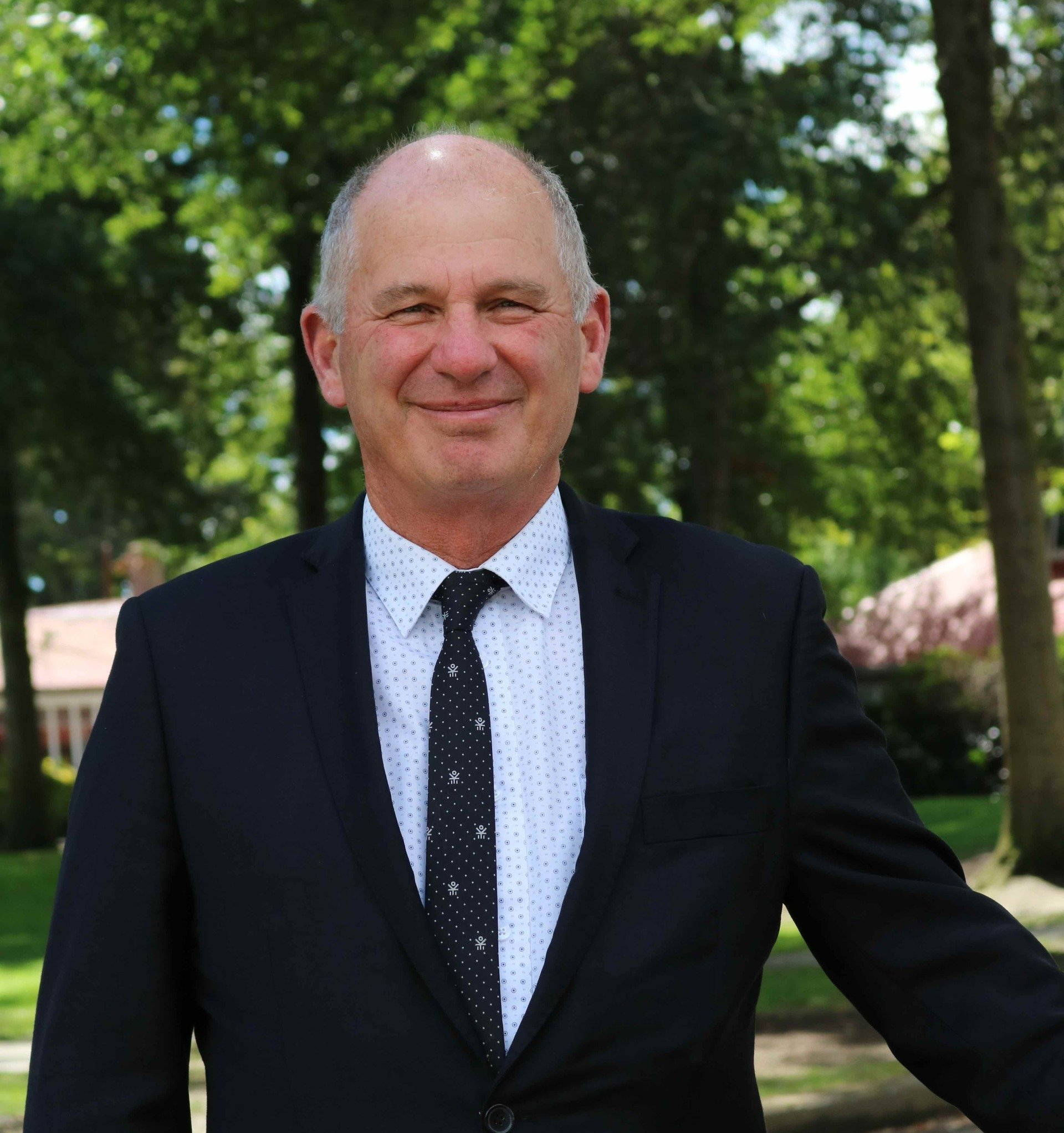 A man in a suit and tie is smiling for the camera