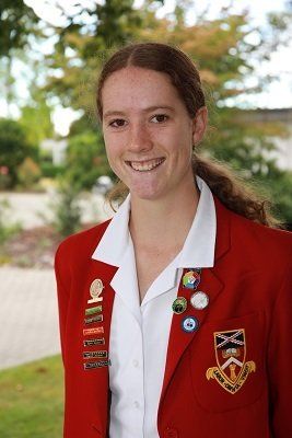 A young woman wearing a red jacket and a white shirt is smiling.