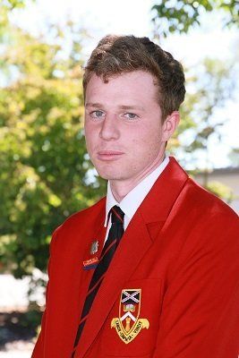 A young man wearing a red jacket with a crest on it