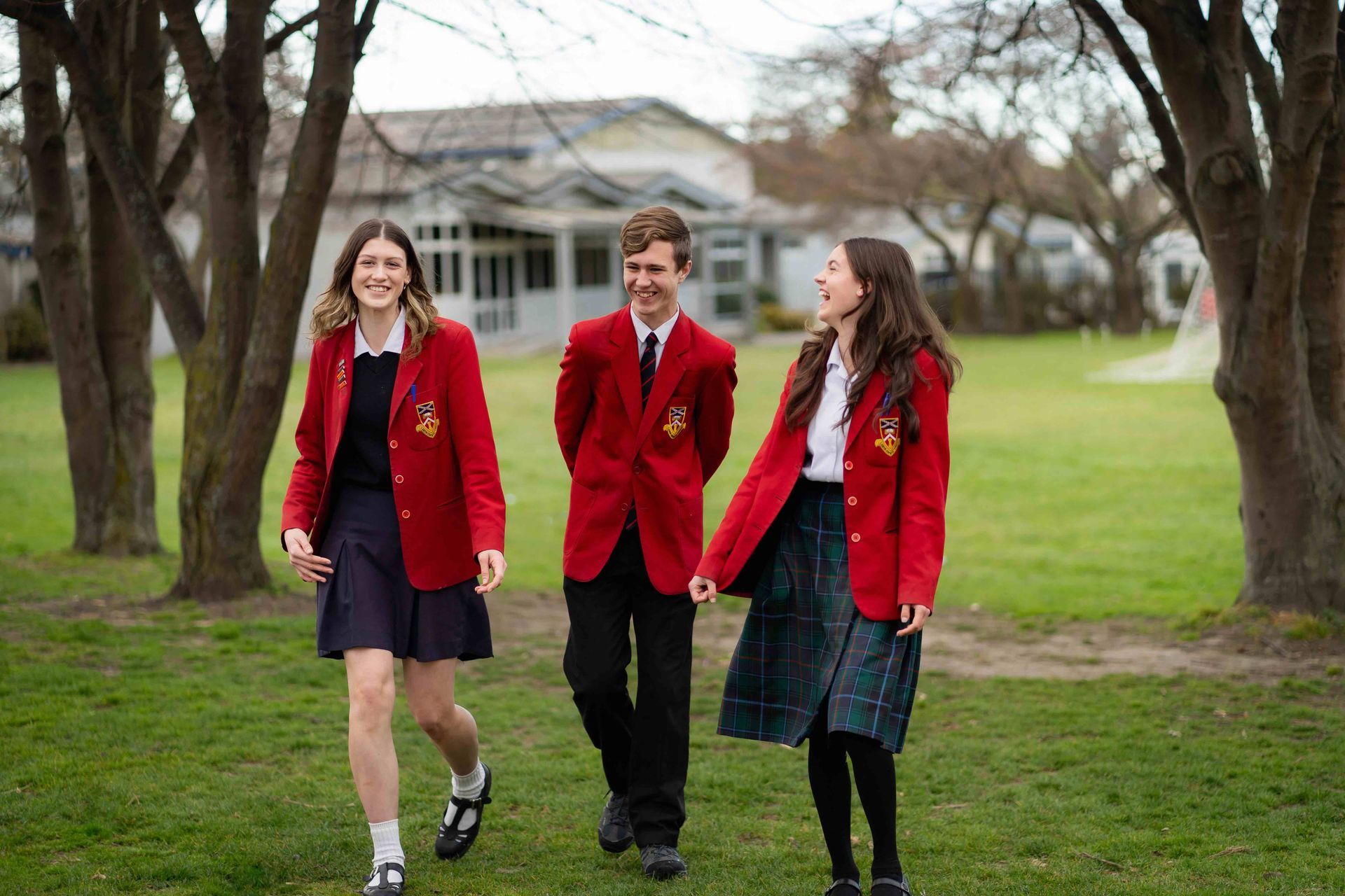 A group of young people in school uniforms are walking in a park.