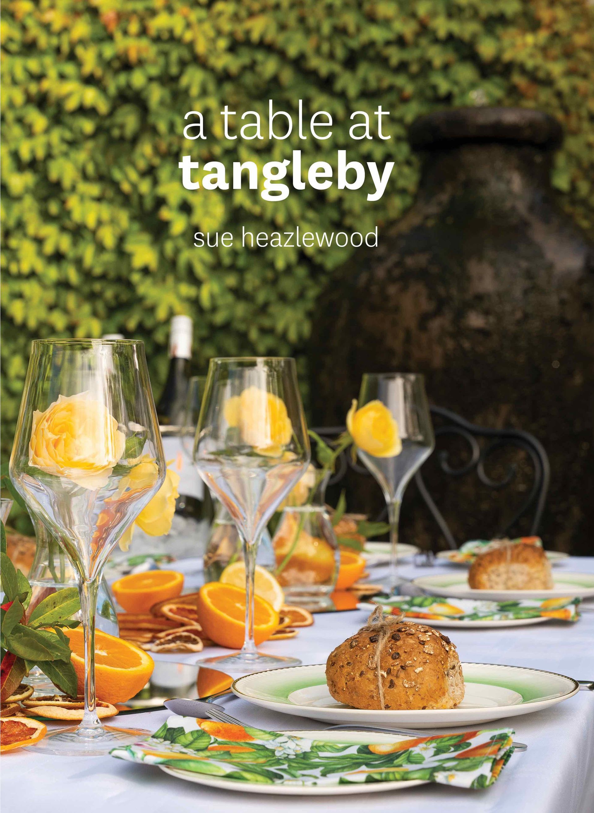 A table with plates , glasses , and oranges on it.