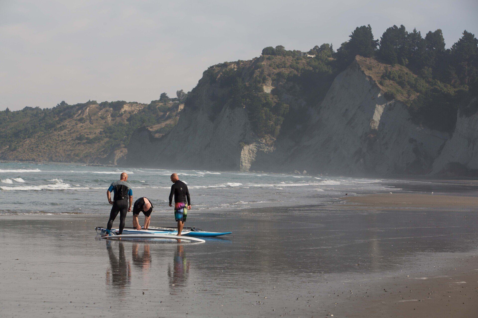 A group of people are standing on a beach with surfboards.