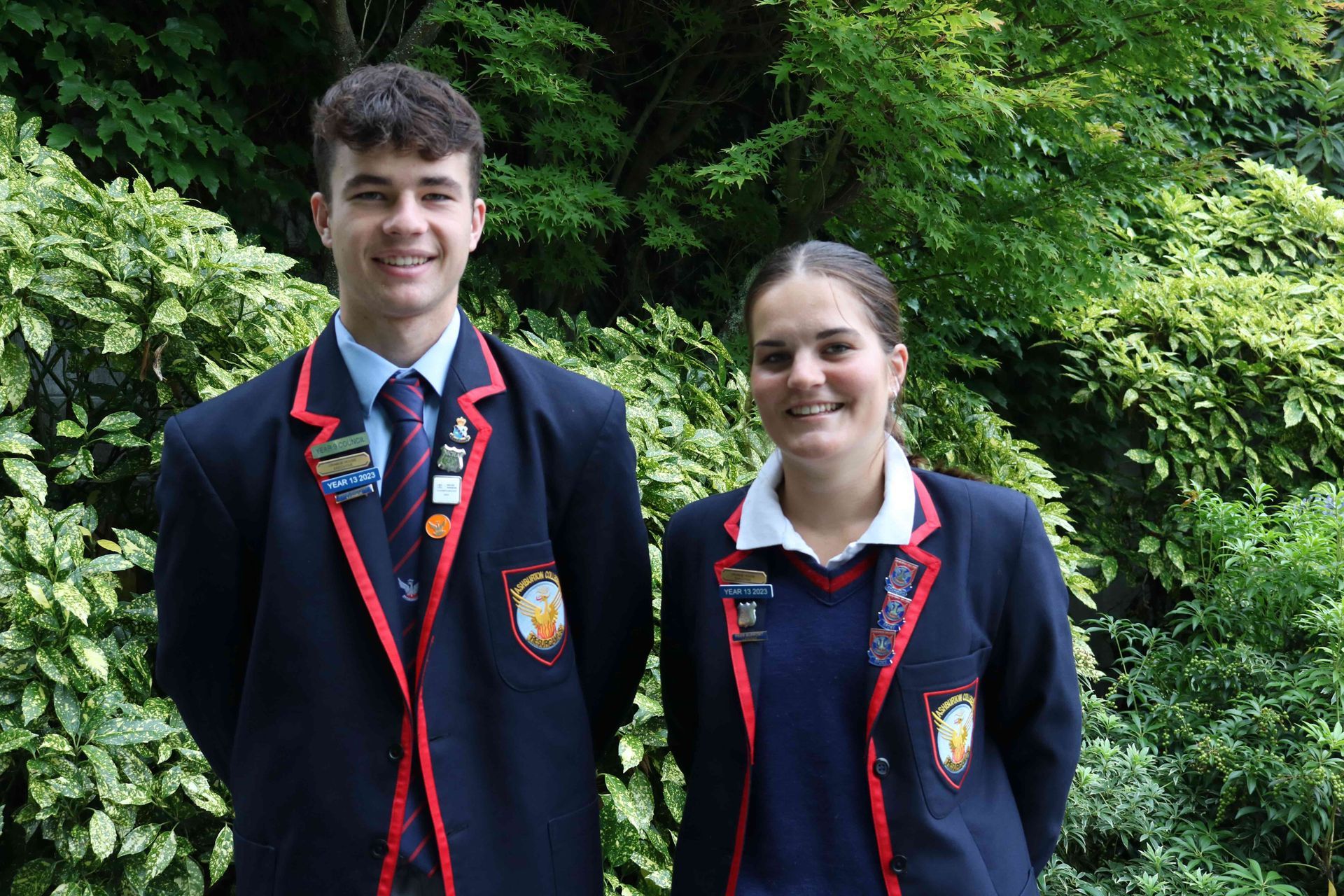 A boy and a girl in school uniforms are posing for a picture.