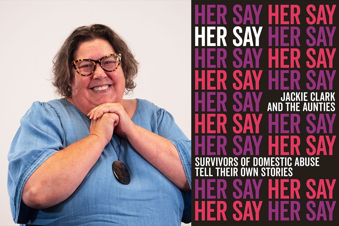 A woman is smiling in front of a poster that says her say