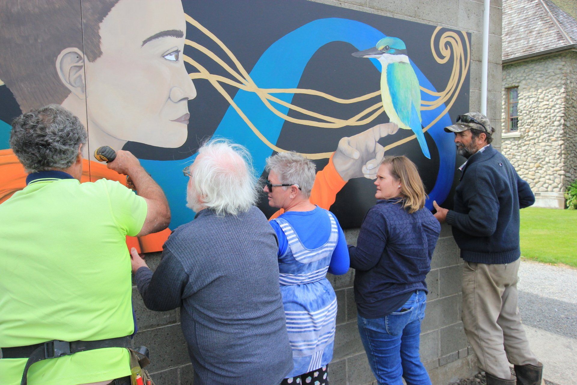 A group of people are working on a mural on a wall.