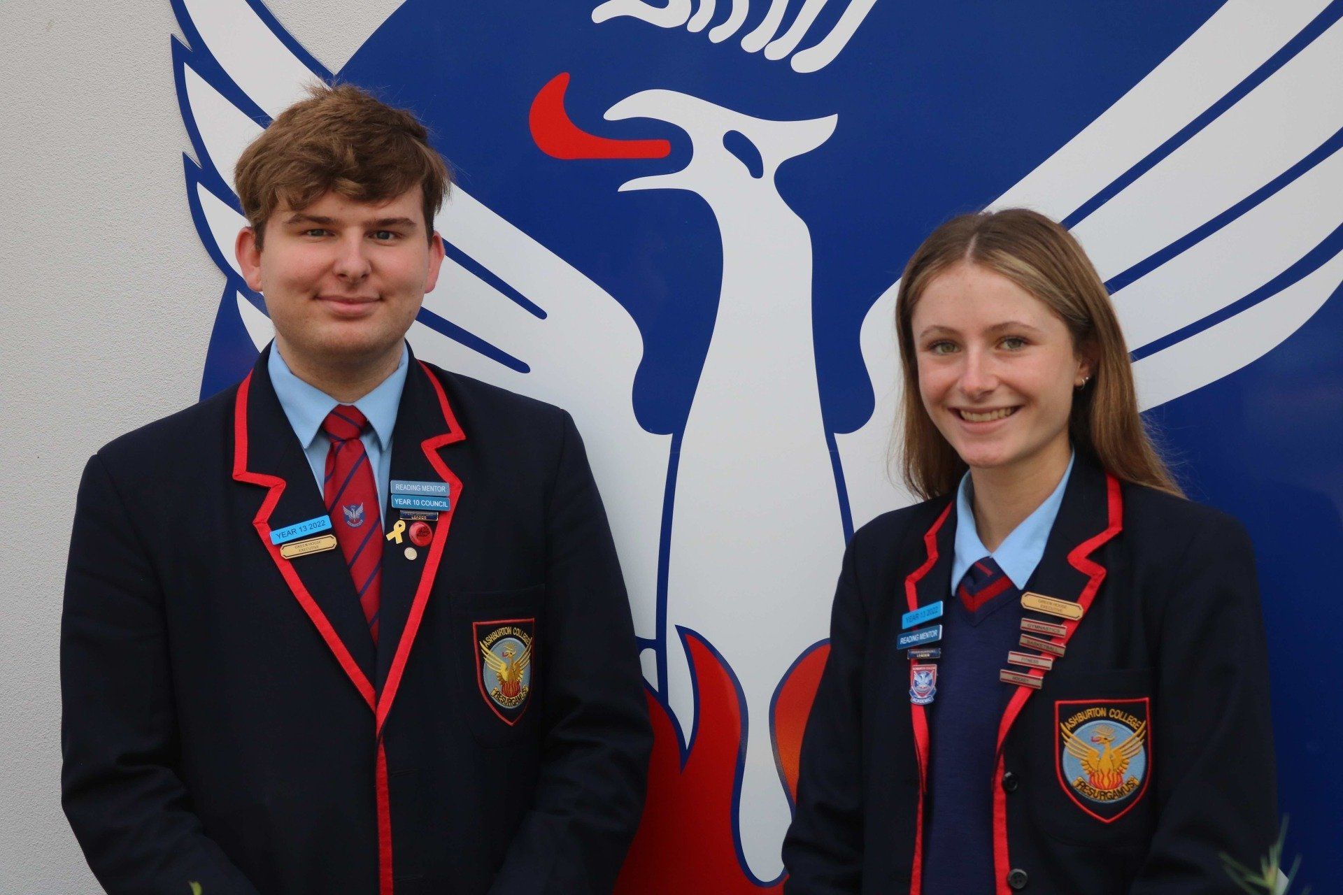 A man and a woman are standing in front of a phoenix logo