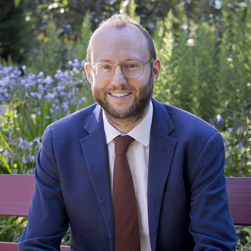 A man in a suit and tie is sitting on a bench.