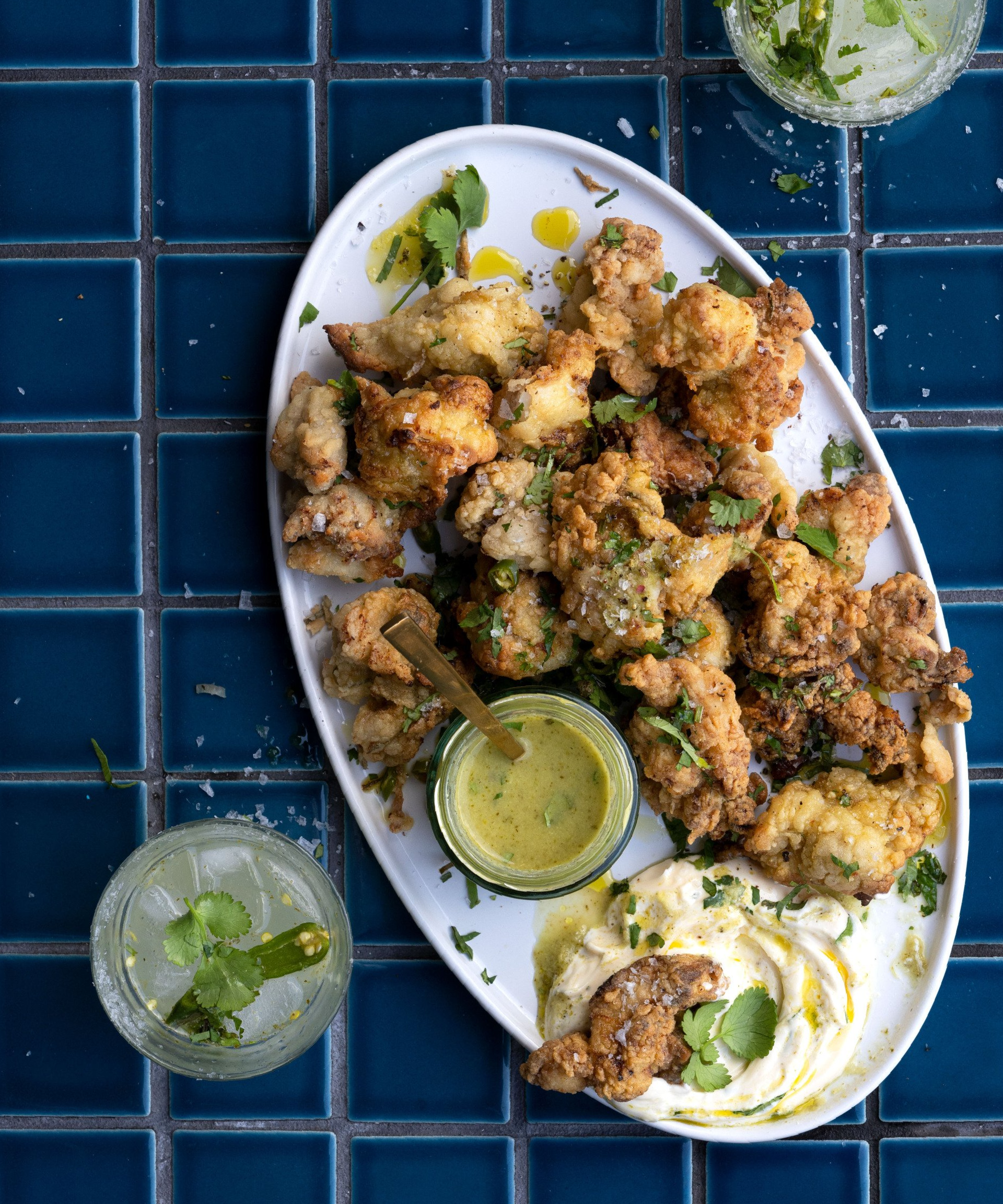 A white plate topped with fried chicken and sauce on a blue tiled table.