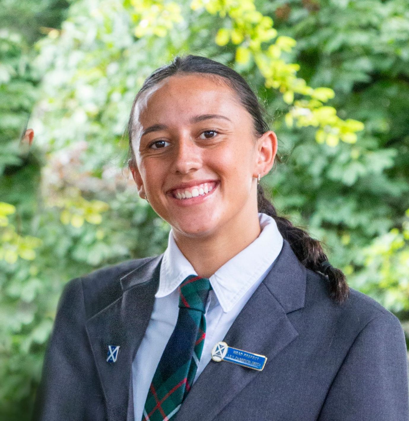 A young woman in a suit and tie is smiling for the camera.