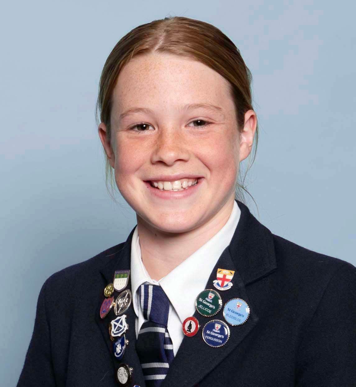 A young girl wearing a suit and tie is smiling for the camera