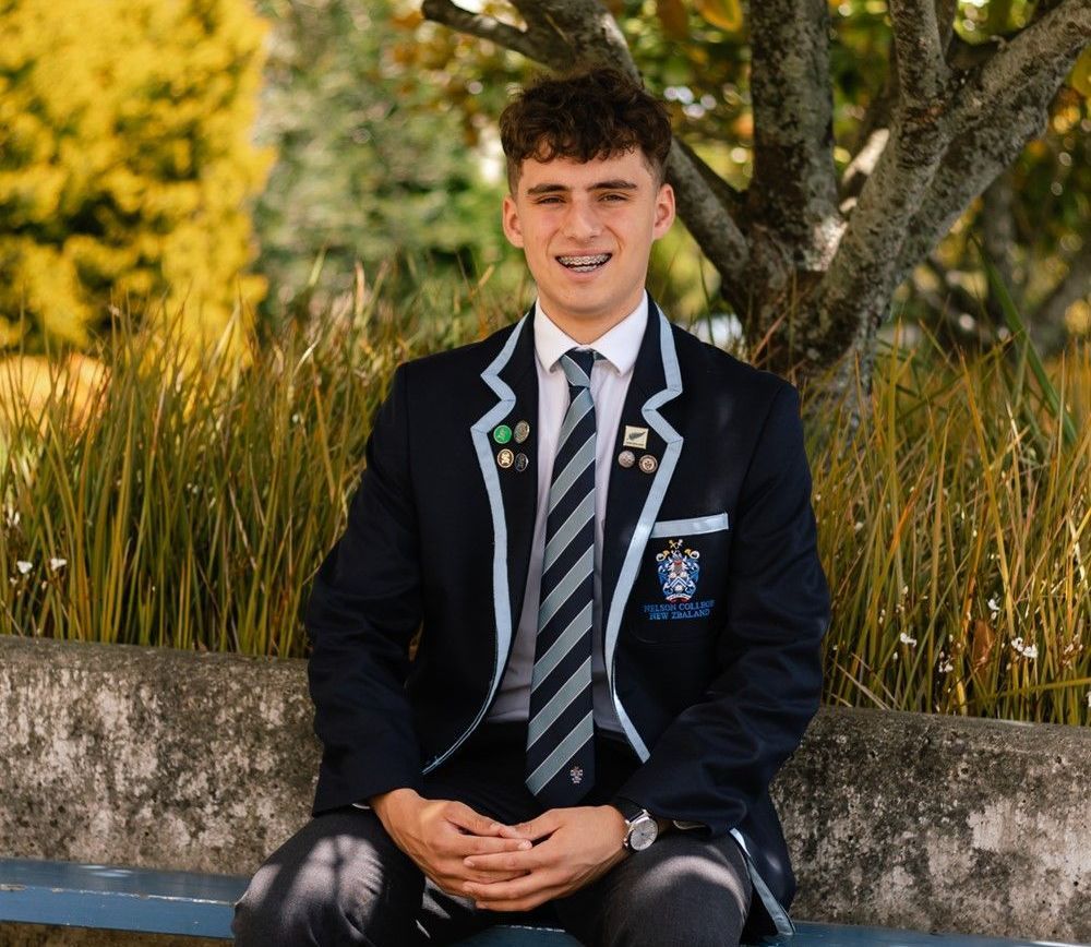 A young man in a suit and tie is sitting on a bench.