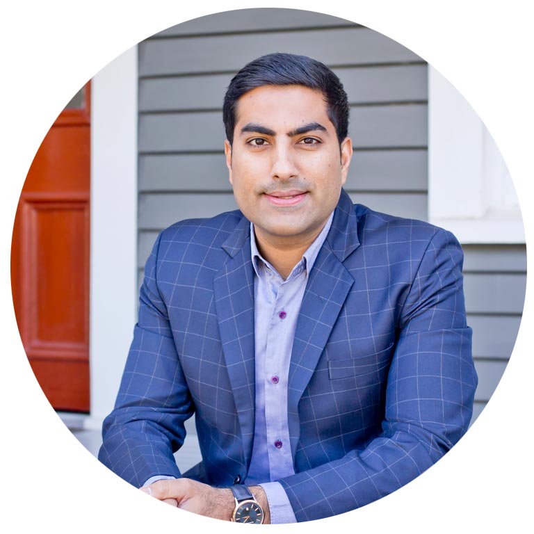 A man in a suit is sitting in front of a house.