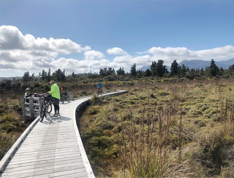 A group of people are riding bikes on a wooden boardwalk.