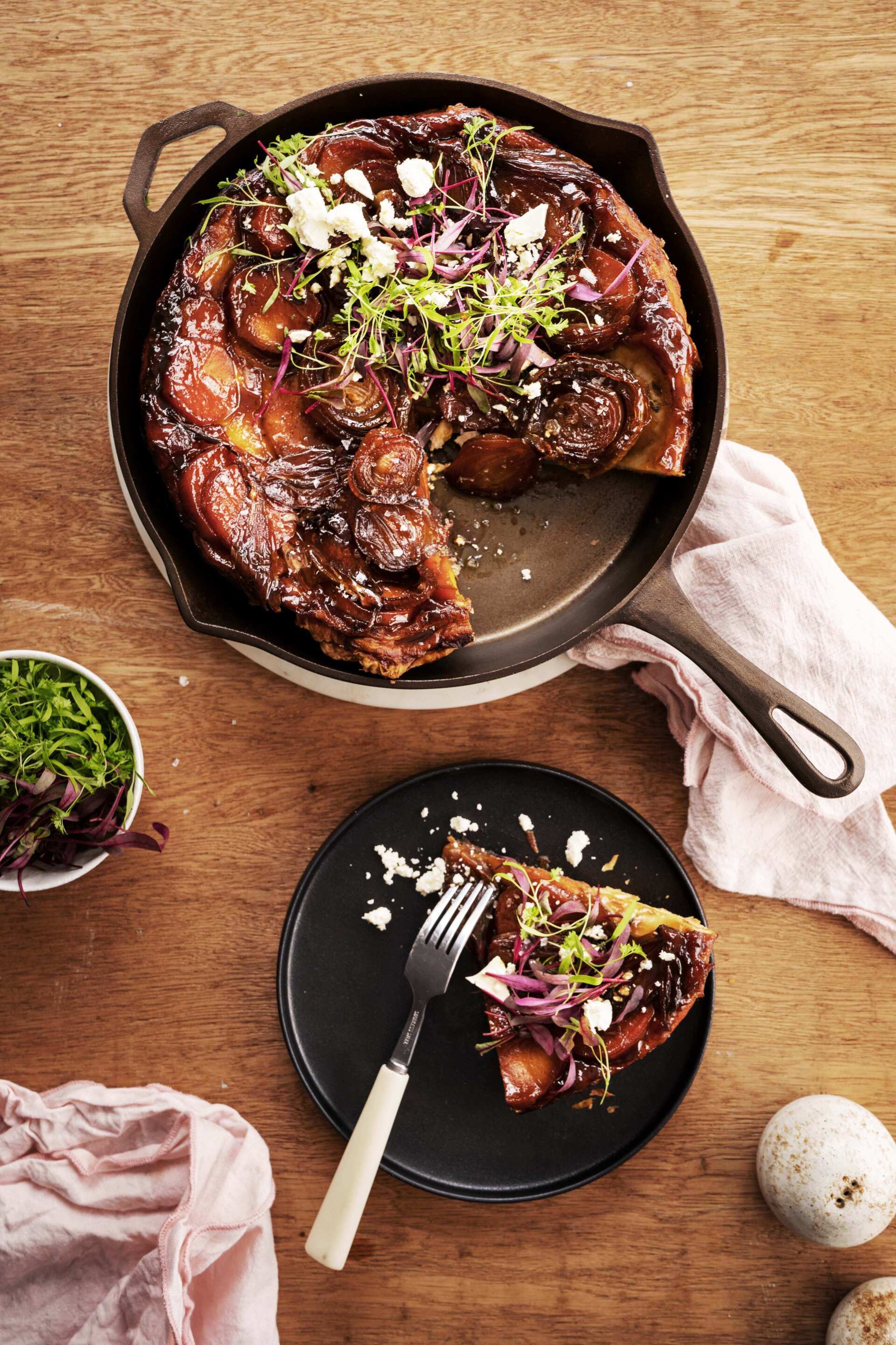 A skillet of food with a slice taken out of it on a plate with a fork.