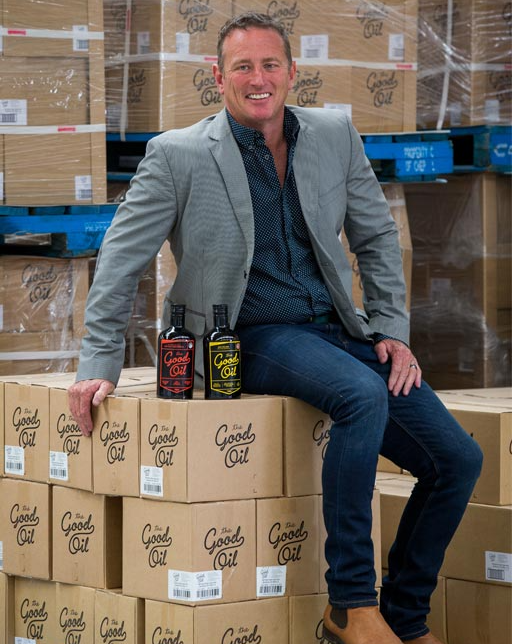 A man is sitting on a stack of boxes that say good oil