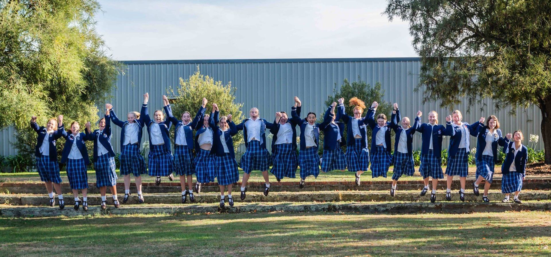 A group of children are standing in a row with their hands in the air.