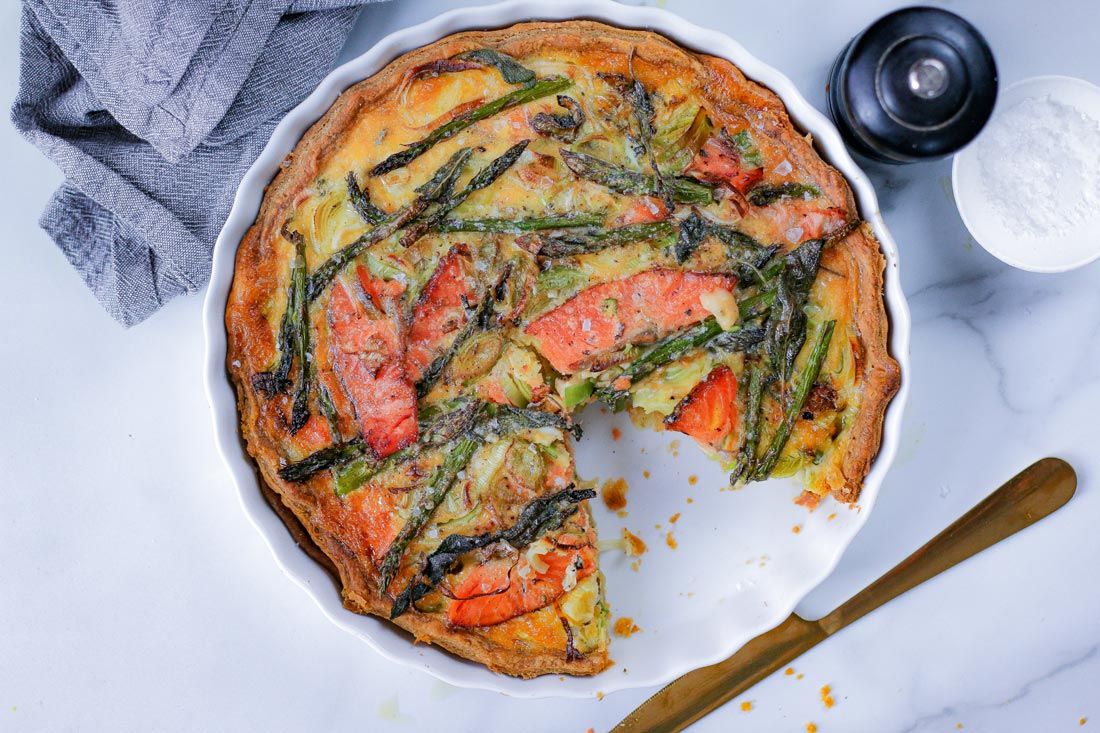 There is a slice taken out of a quiche in a pan.