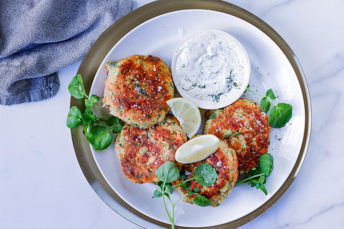 A white plate topped with crab cakes and ranch dressing.