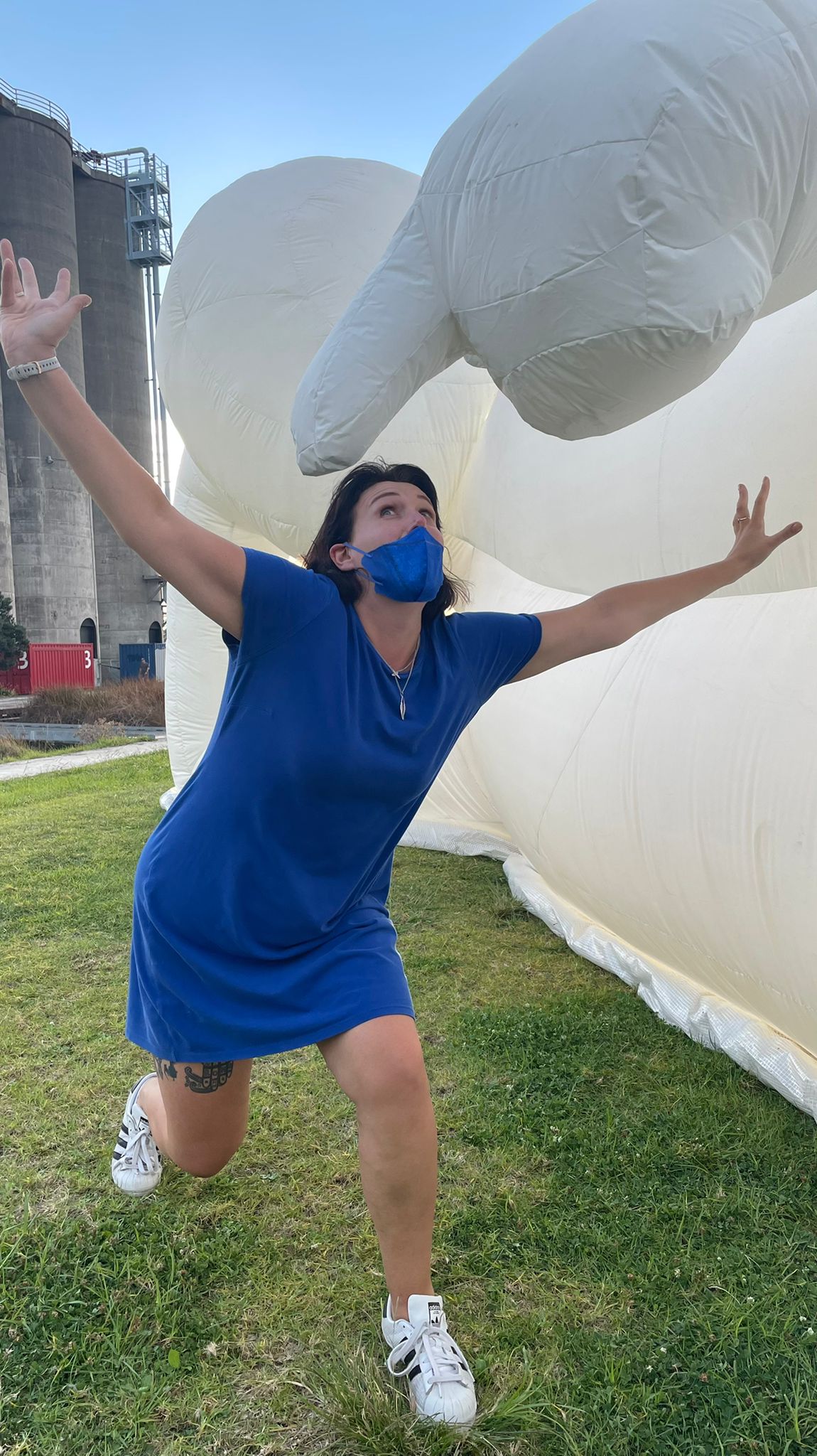 A woman wearing a blue mask is standing in front of a large inflatable elephant.