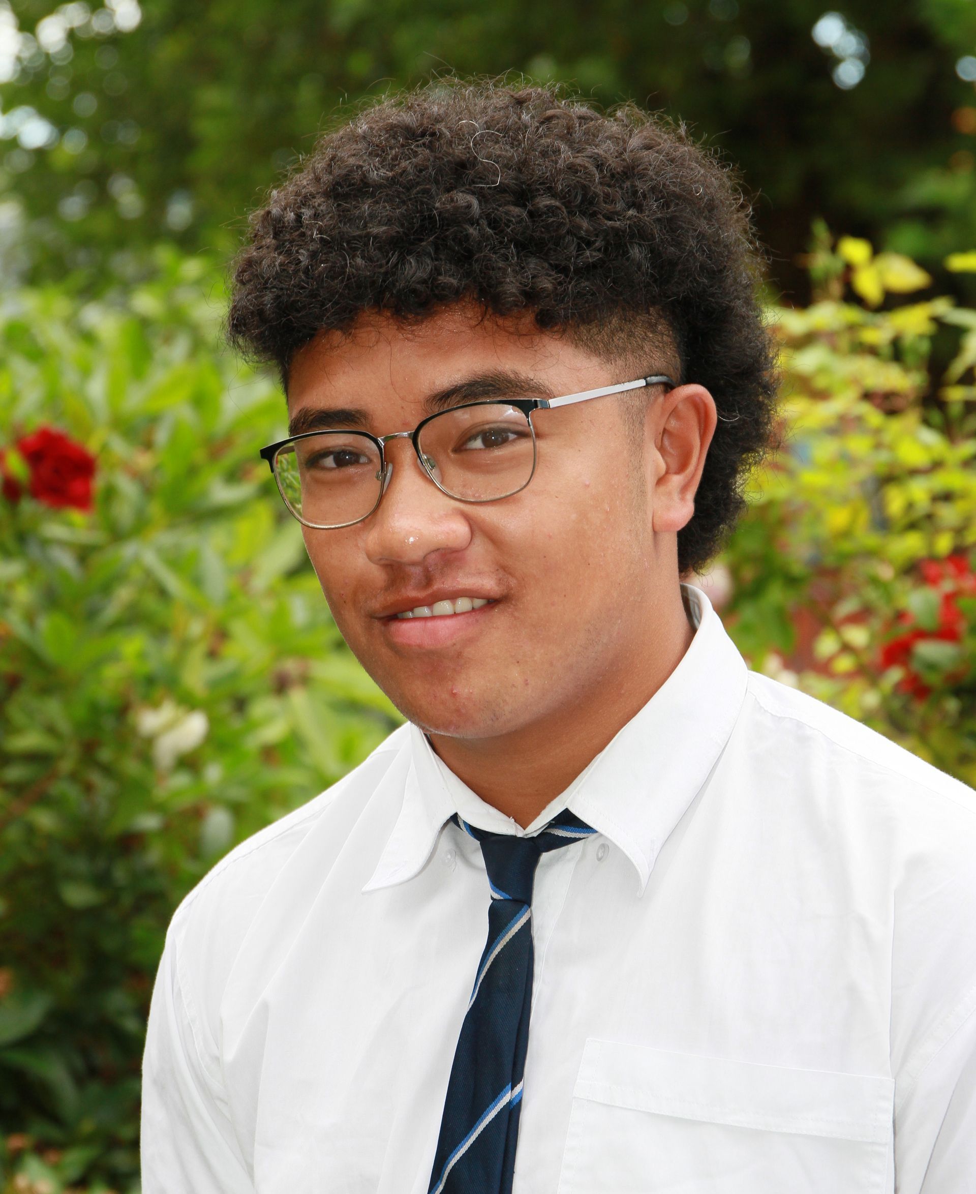 A young man wearing glasses and a tie is smiling for the camera.