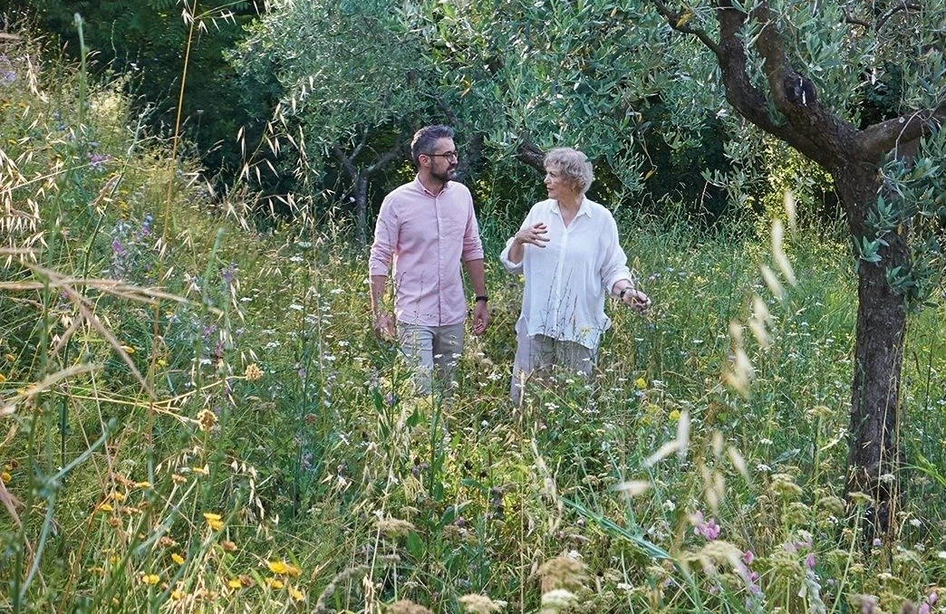 A man and a woman are walking through a field of tall grass.