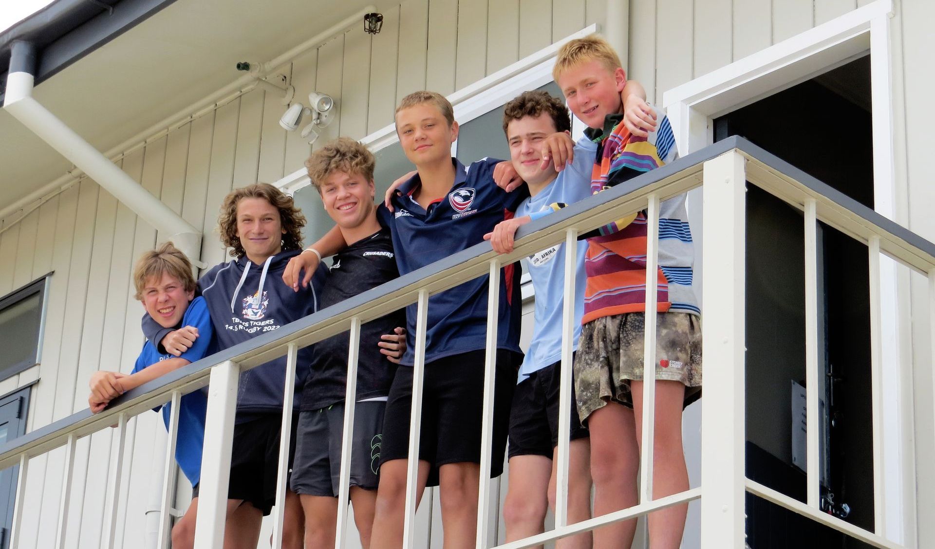 A group of young men are standing on a balcony.