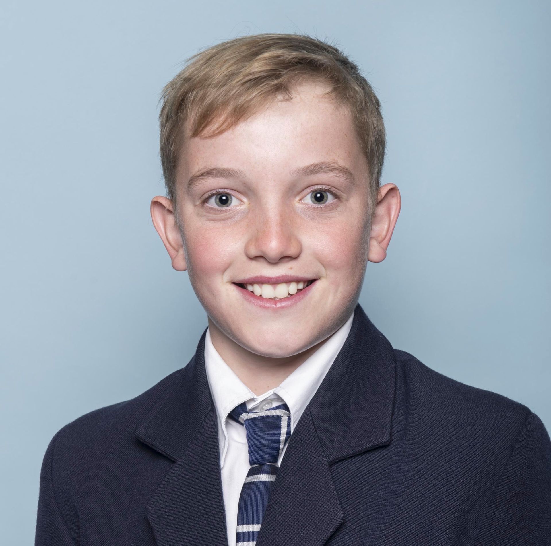 A young boy wearing a suit and tie is smiling for the camera