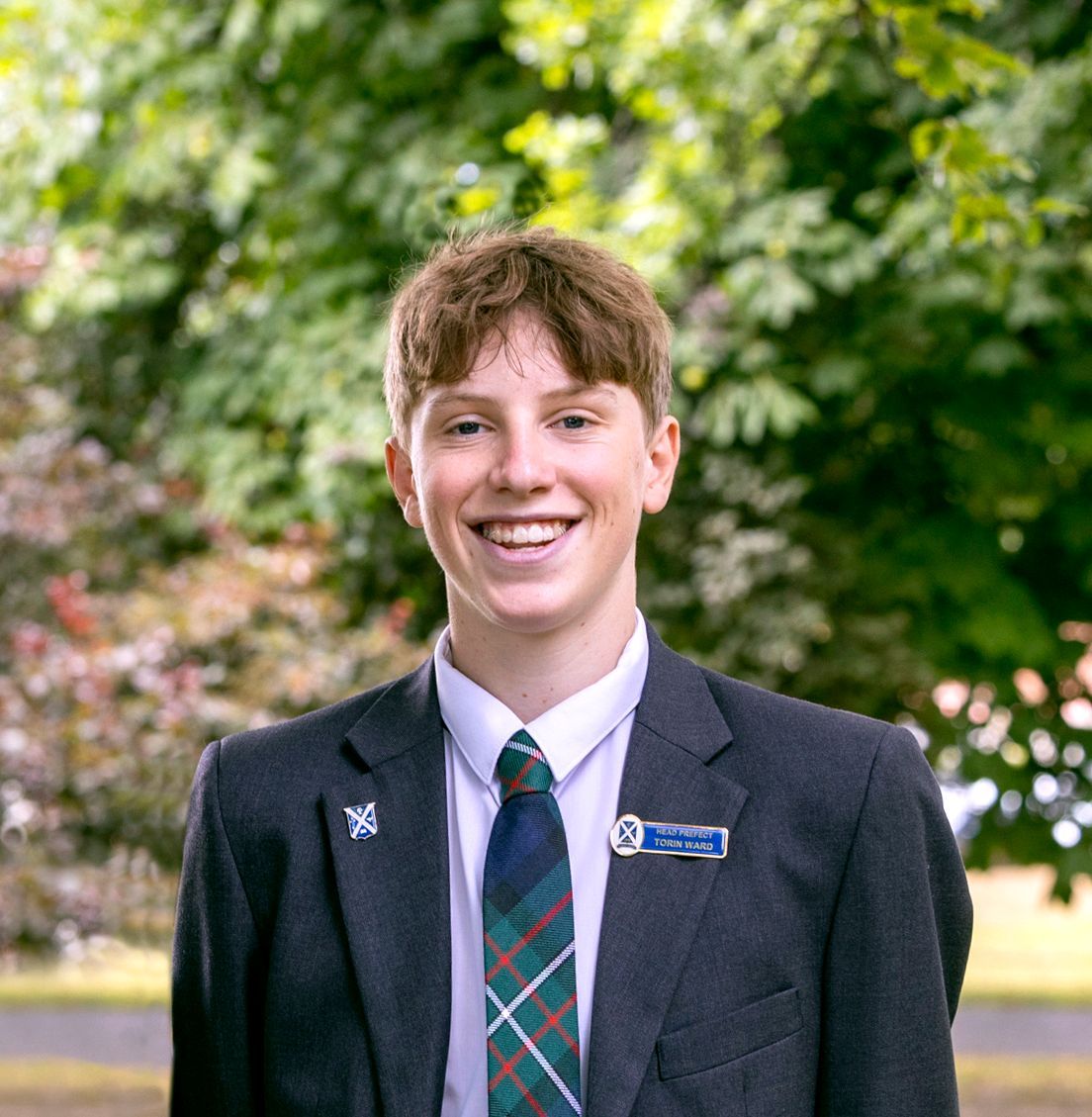 A young man in a suit and tie is smiling for the camera.