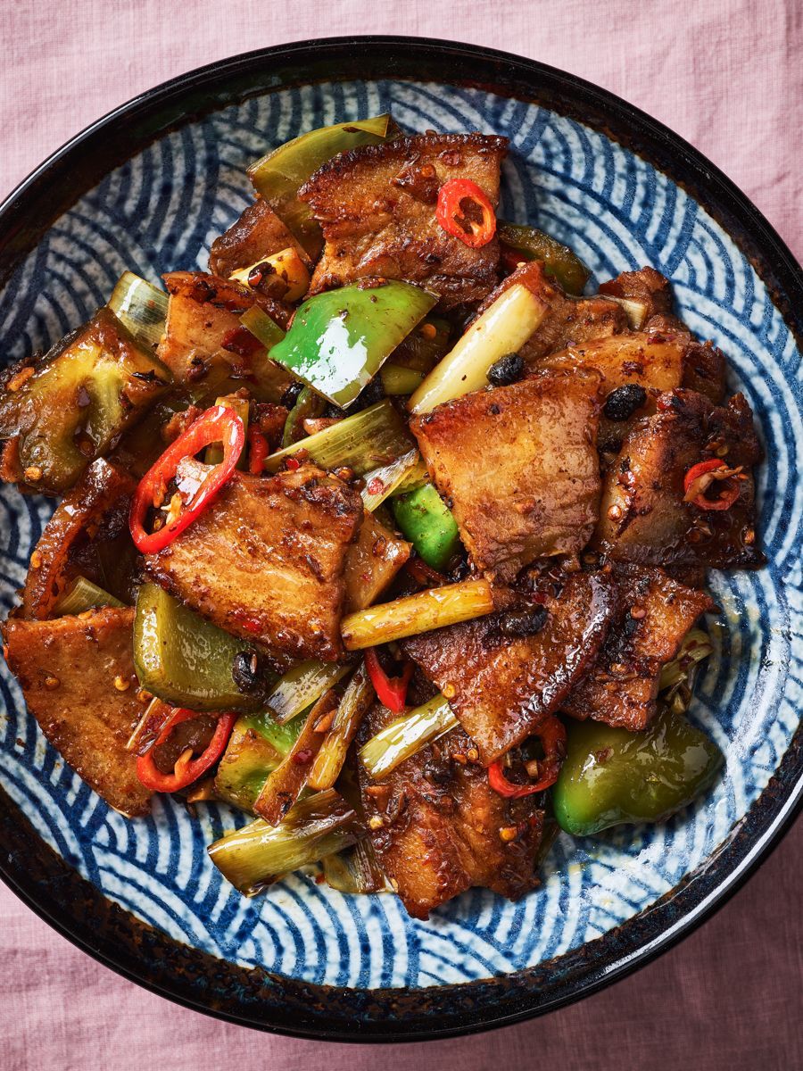 A bowl of food with meat and vegetables on a table.