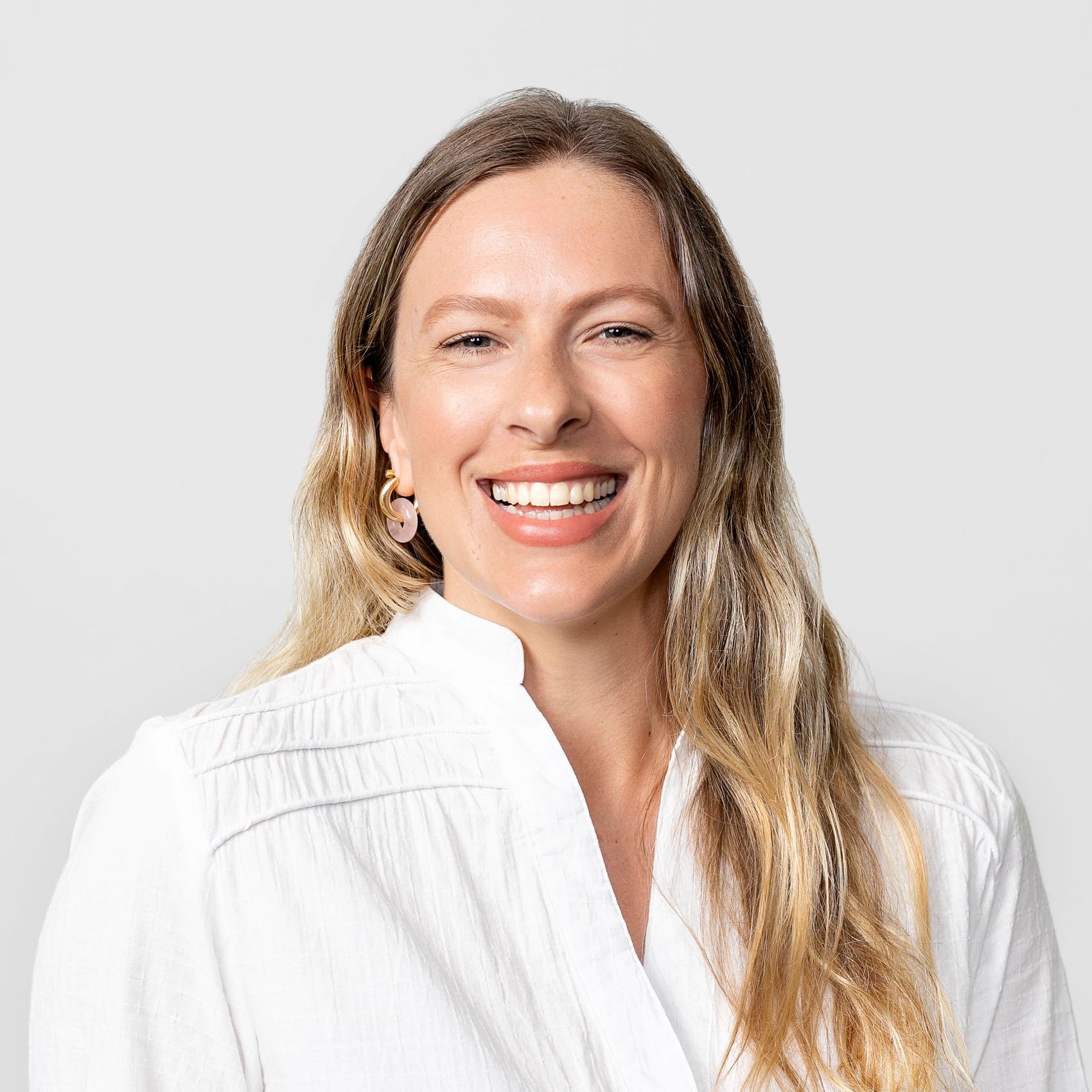 A woman in a white shirt is smiling for the camera.