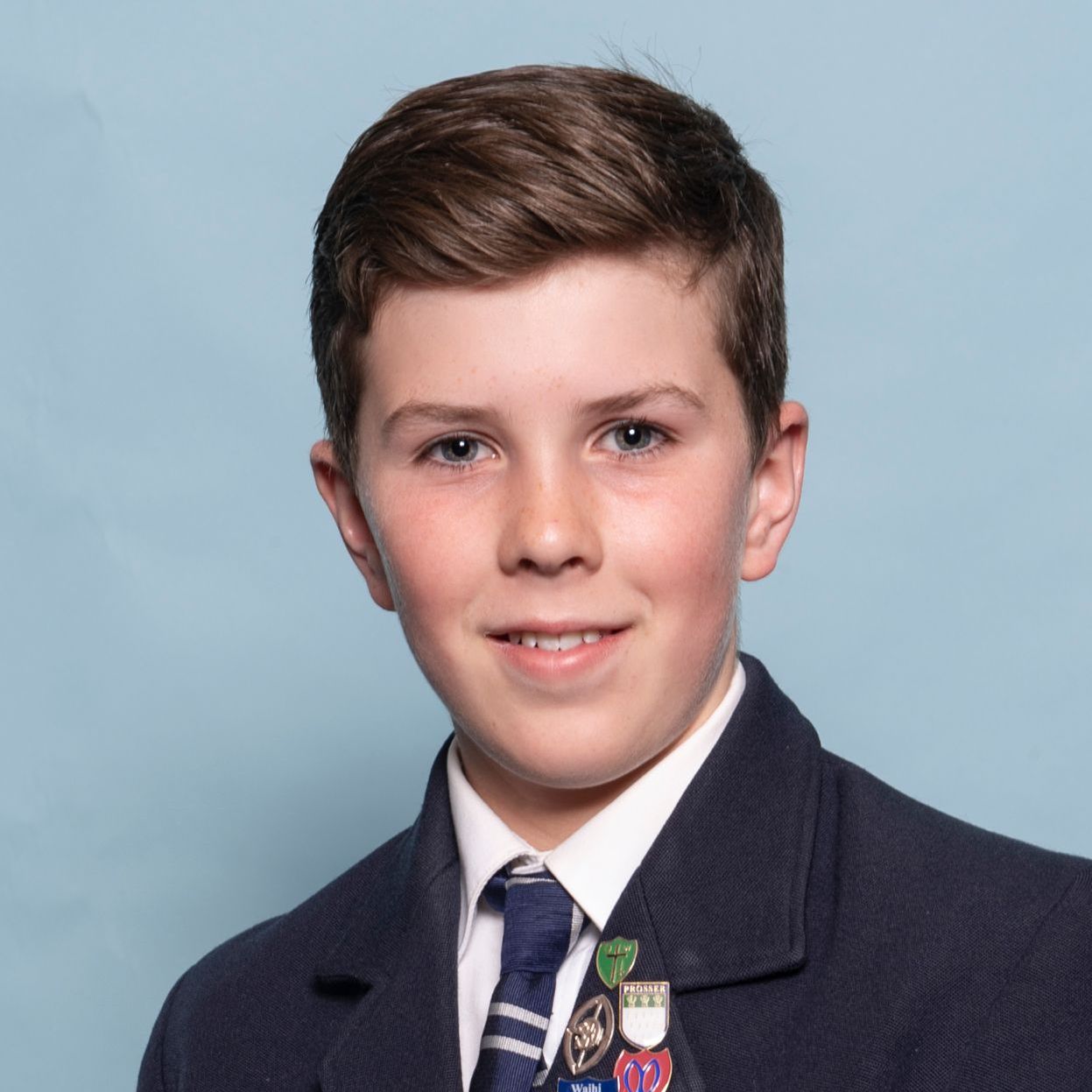 A young boy in a suit and tie is smiling for the camera