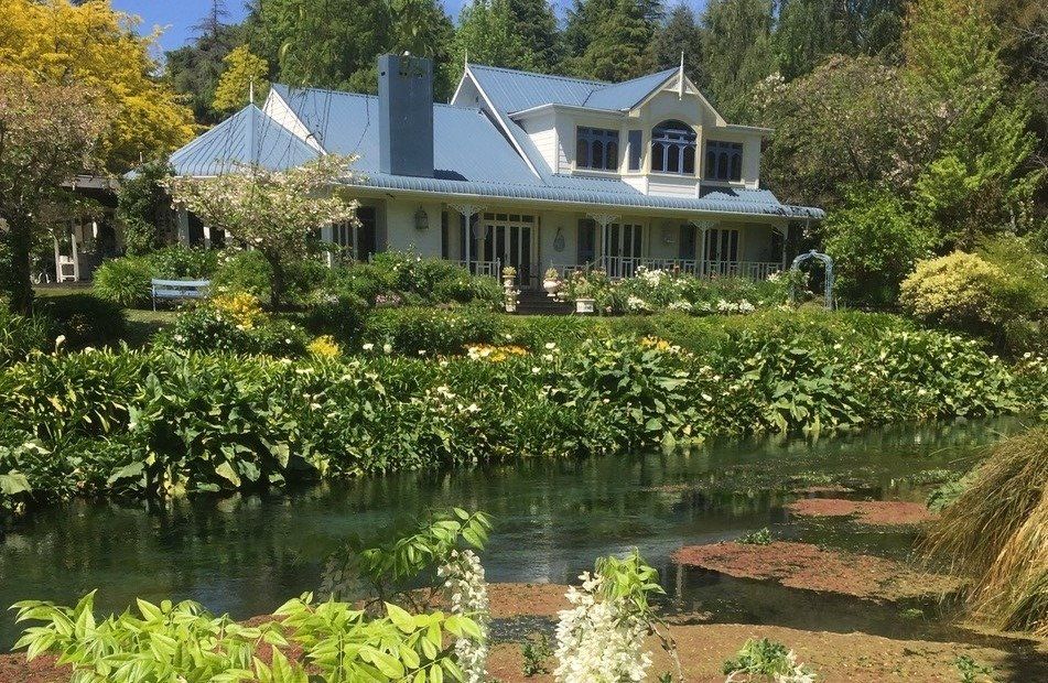 A large house with a pond in front of it surrounded by trees.