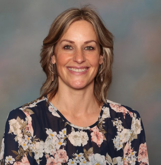 A woman wearing a floral shirt is smiling for the camera