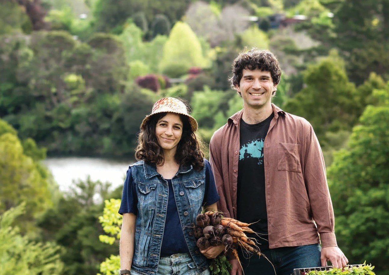 A man and a woman are standing next to each other holding carrots.