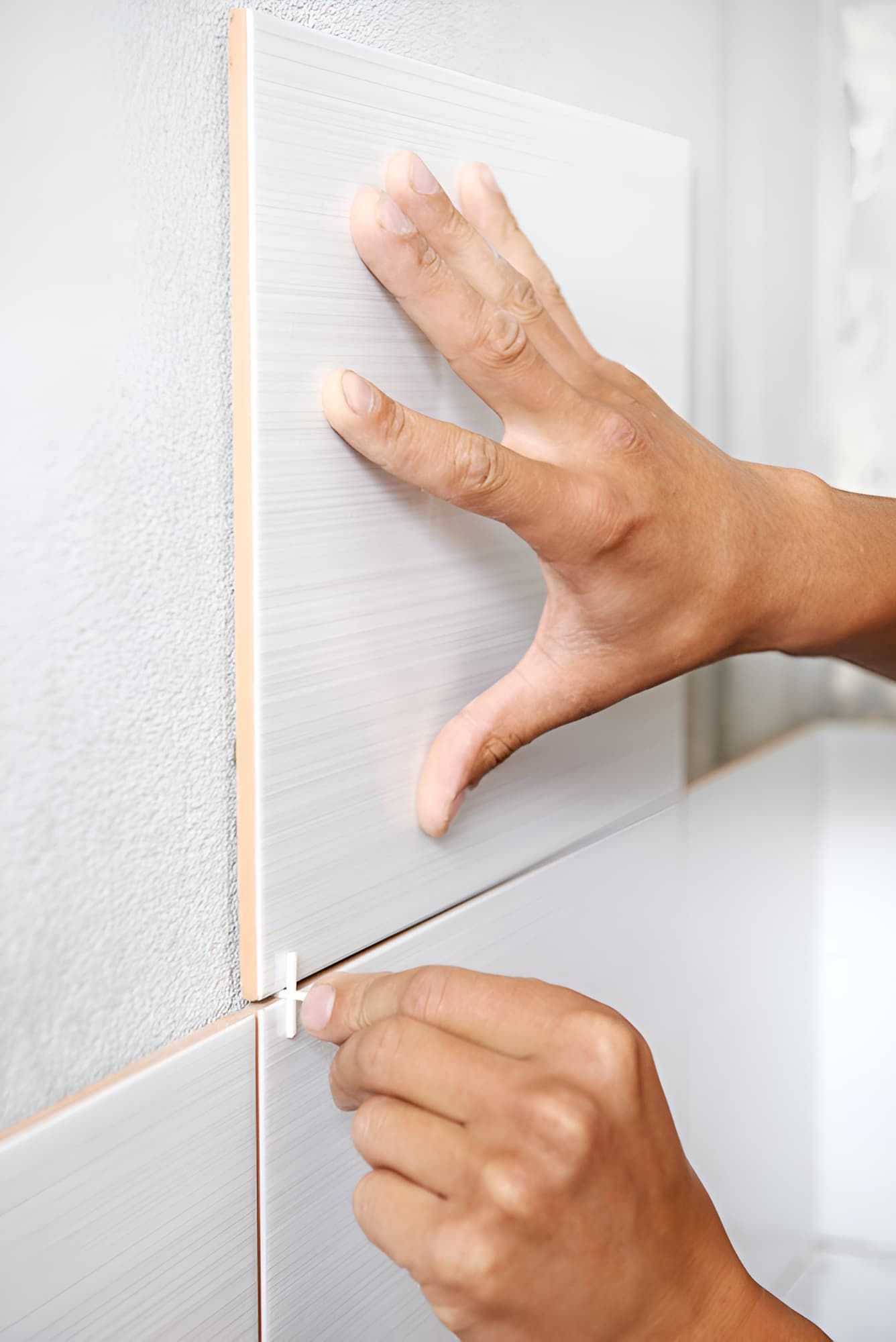 A Person is Installing a Tile on a Wall — Simpson's Plumbing & Maintenance Service in Dakabin, QLD