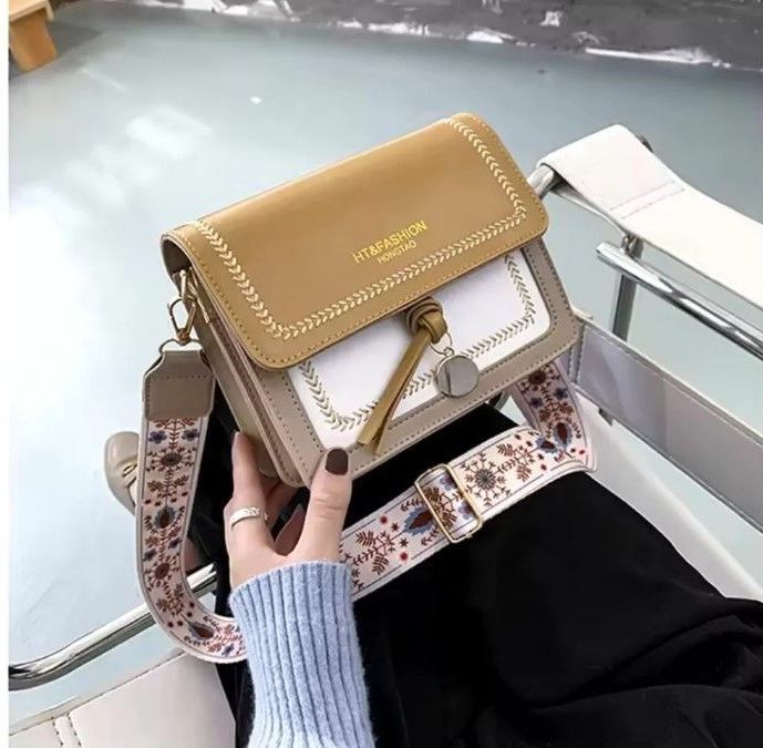Una mujer está sentada en una silla sosteniendo un bolso.