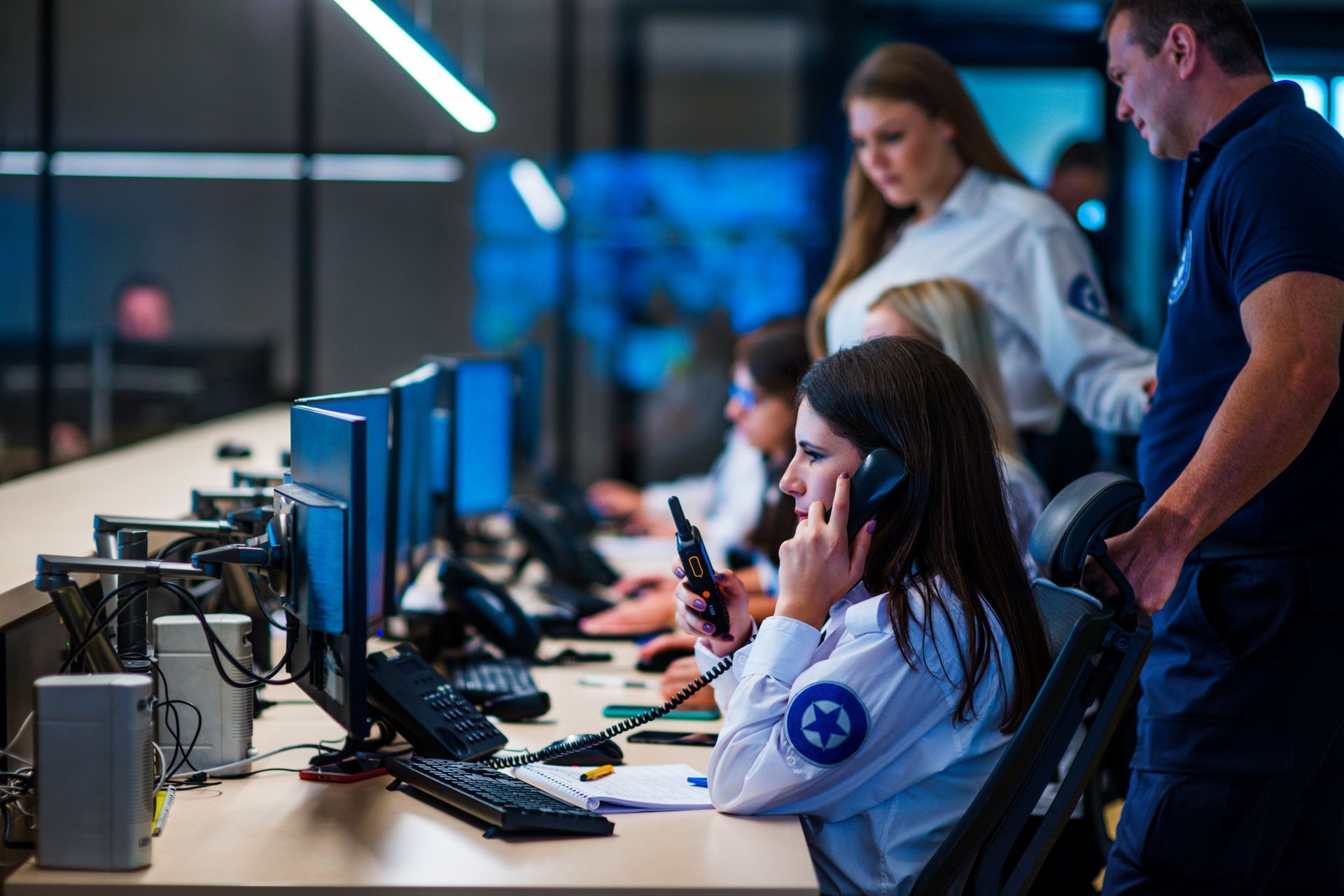 A woman is talking on a cell phone while sitting at a desk in front of a computer.