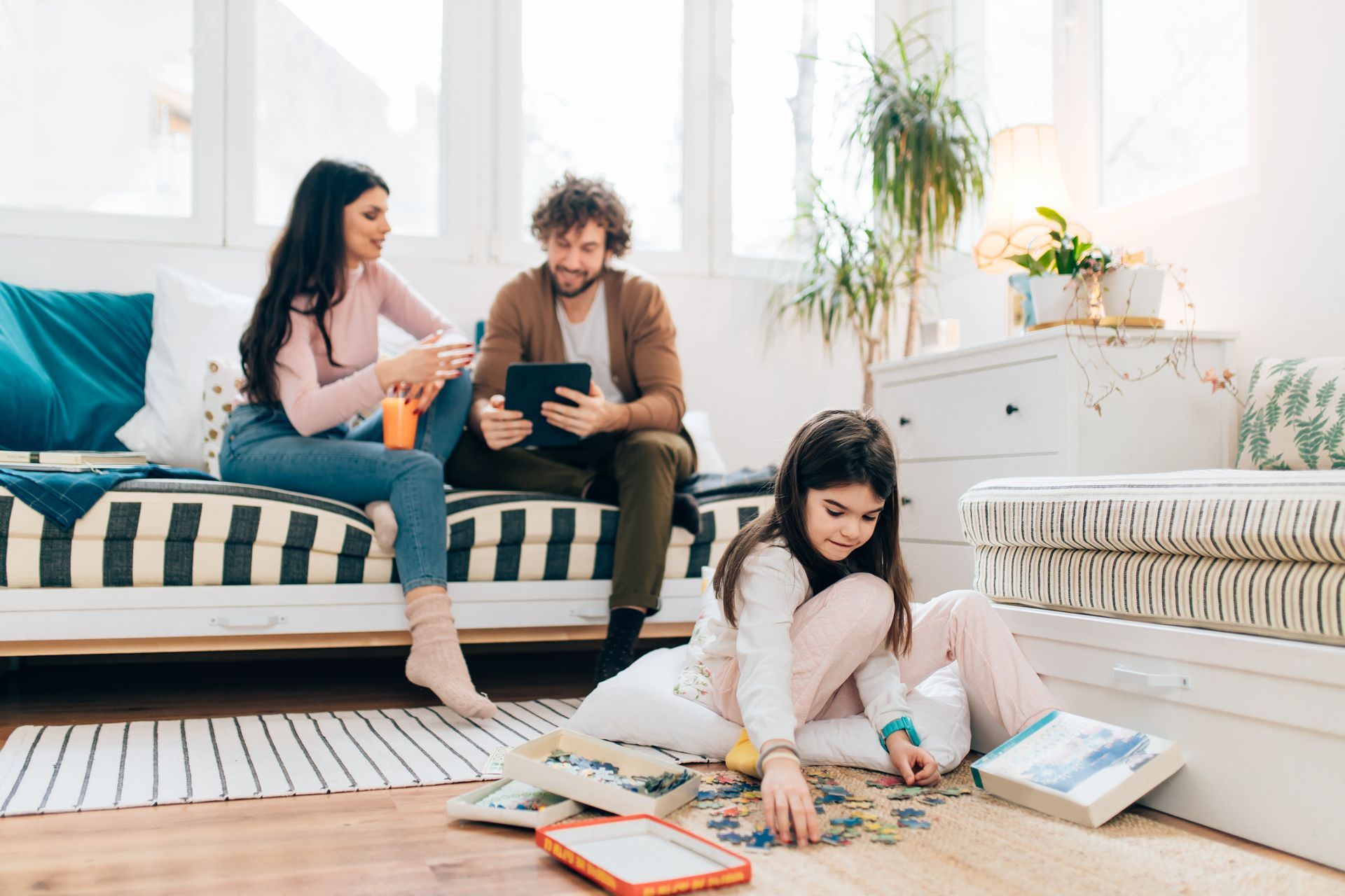 A family is sitting on the floor in a living room playing with puzzles.