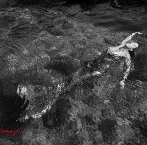 A black and white photo of a woman floating in the water.