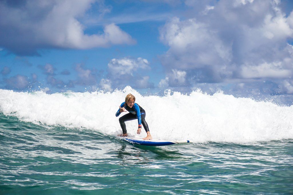 A young boy is riding a wave on a surfboard in the ocean.