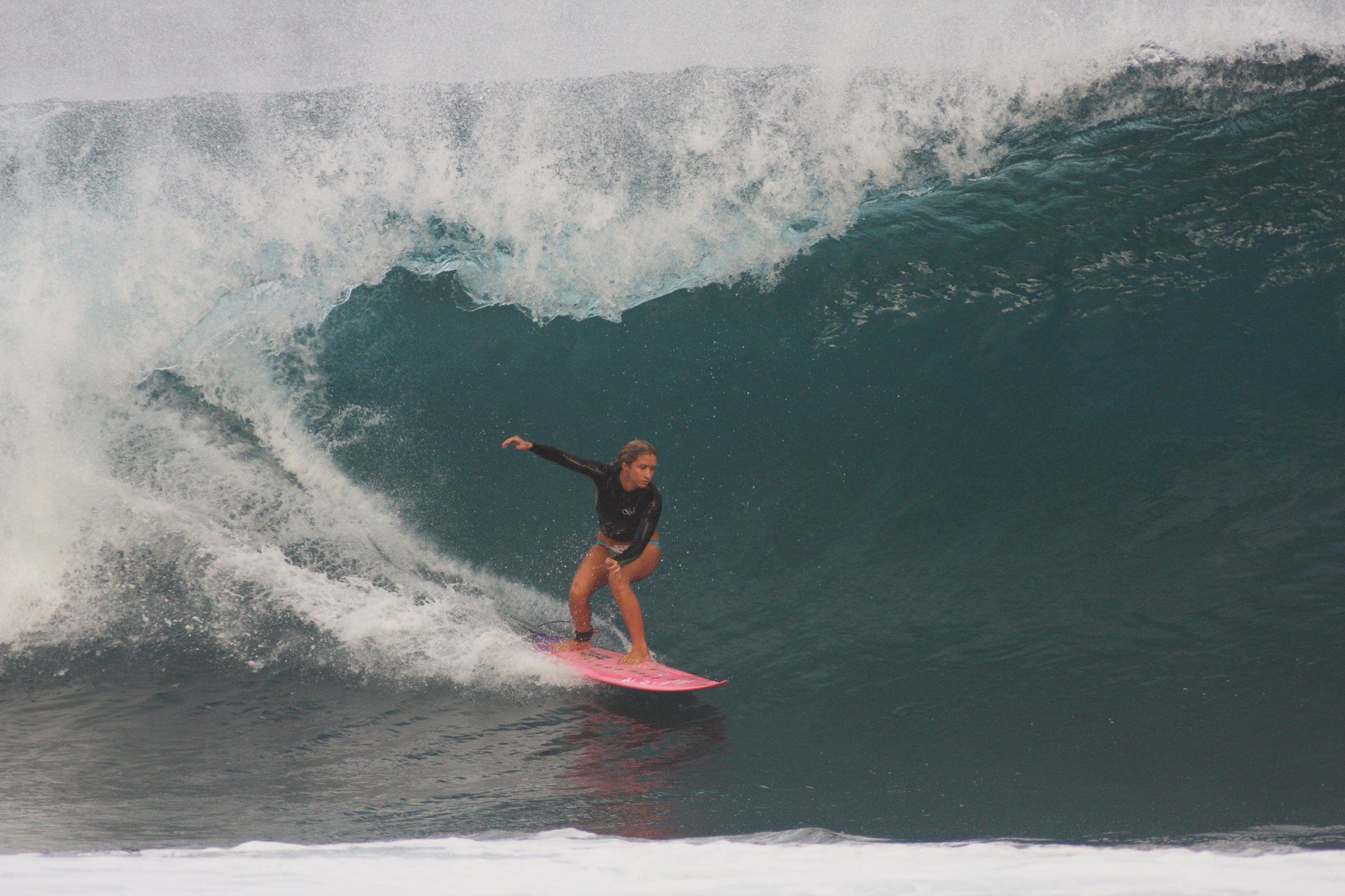 A woman is riding a wave on a surfboard in the ocean.
