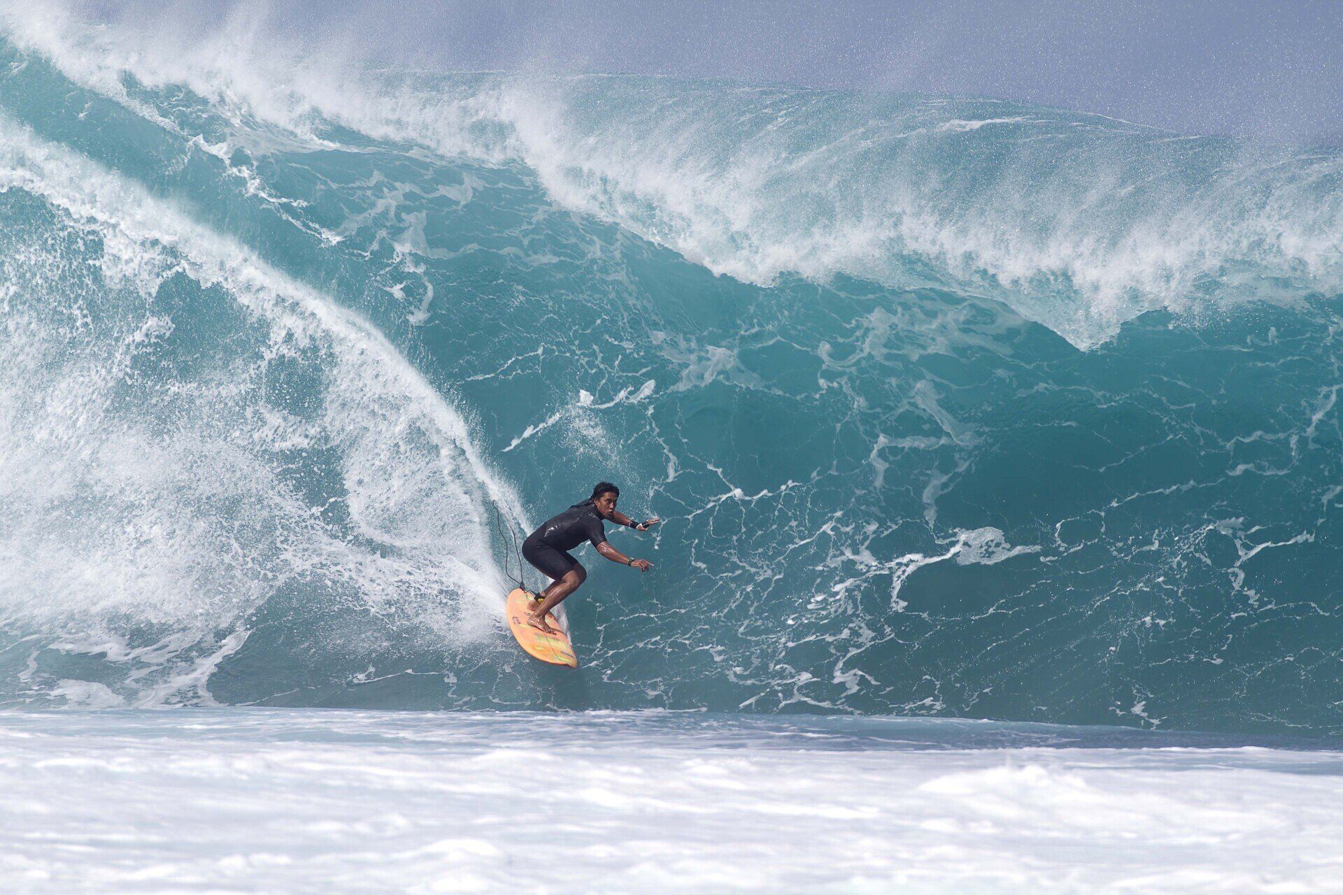 A man is riding a wave on a surfboard in the ocean.