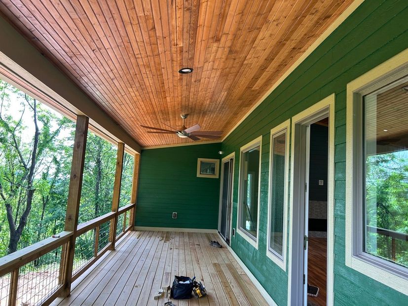 A screened in porch with green walls and a ceiling fan