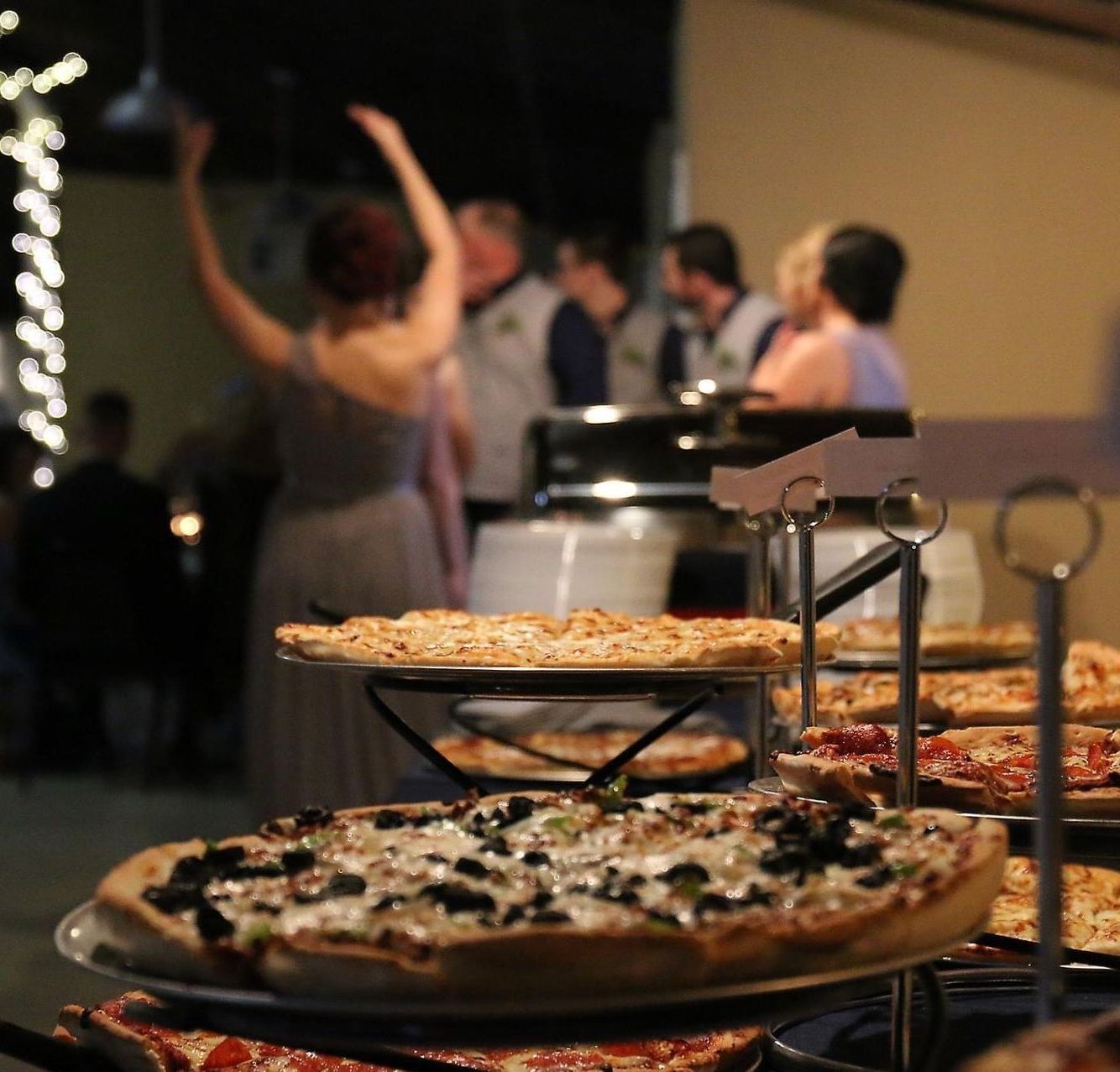 a group of people are dancing in the background behind a display of pizzas