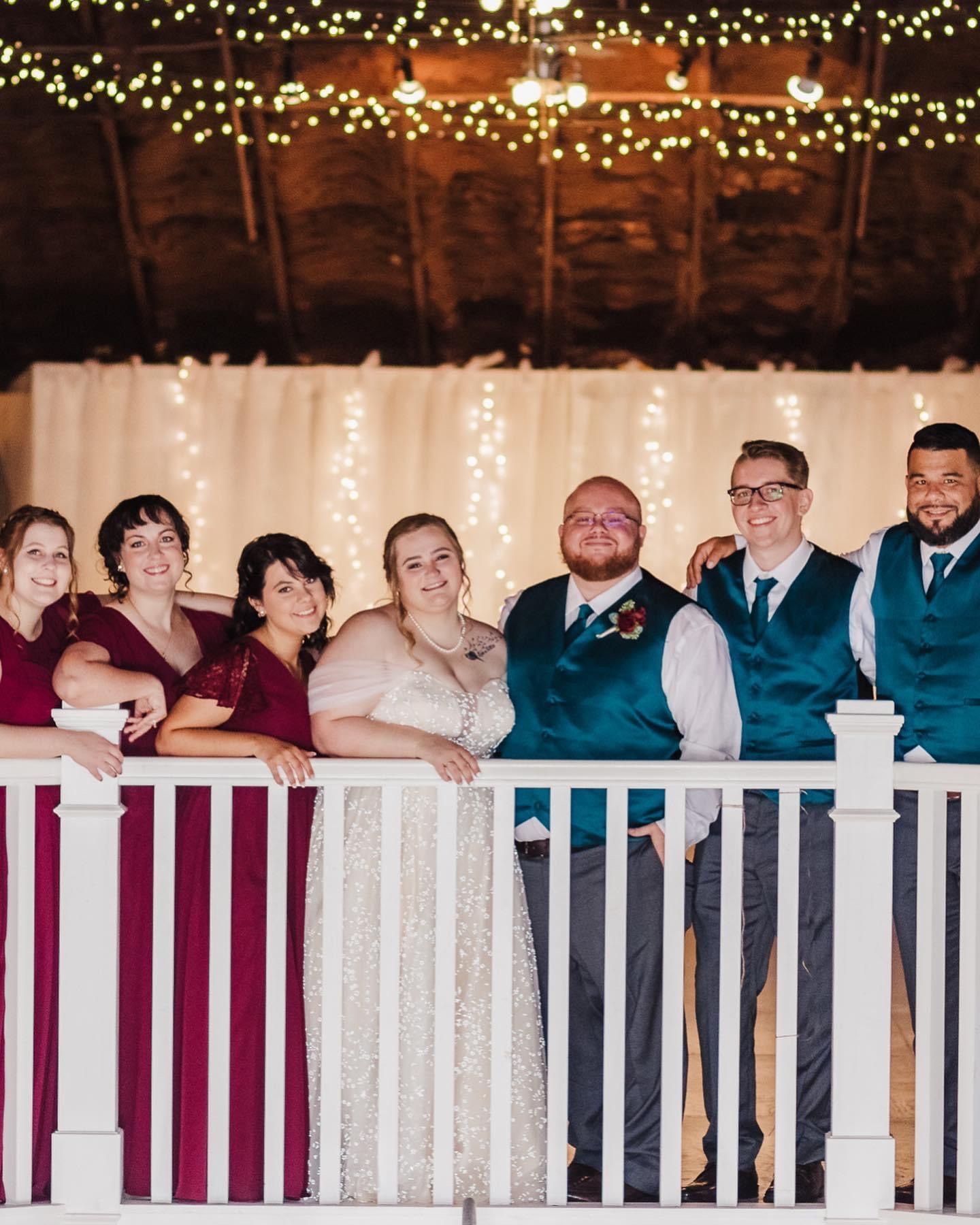 a bride and groom are posing for a picture with their wedding party on a balcony .
