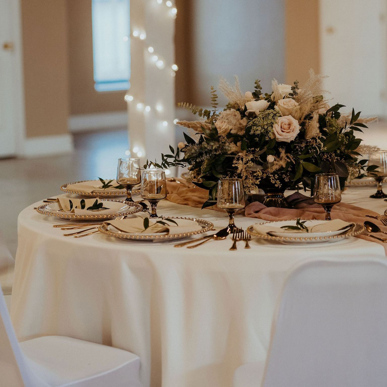a table set for a wedding reception with flowers in the center