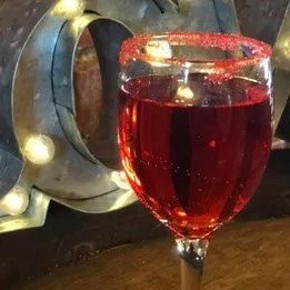 a glass of red wine with a sugar rim on a table .