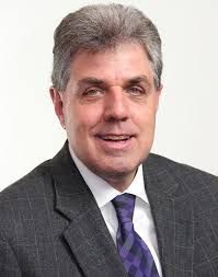 A man is holding a dog in his arms and the dog is wearing a sweater.